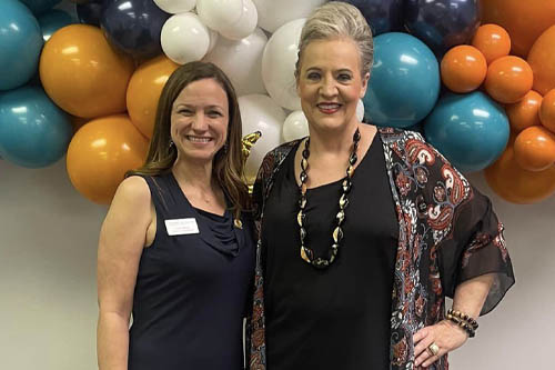 Two Women Pose for a Photo in Front of Multi-Color Balloons at an Open House in Lafayette