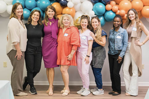 Eight Women Pose for a Photo in Front of Balloons at an Open House in Lafayette