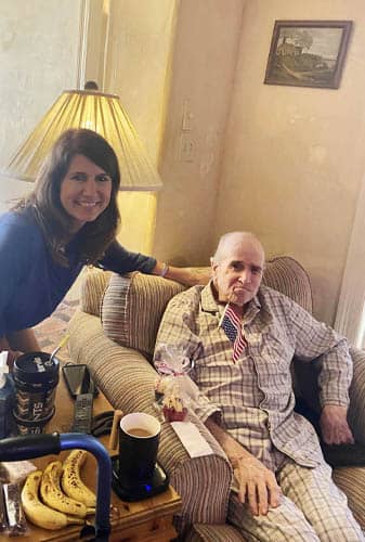 Senior Male Veteran Seated Posing with Female Caregiver and Packaged Gift Muffins