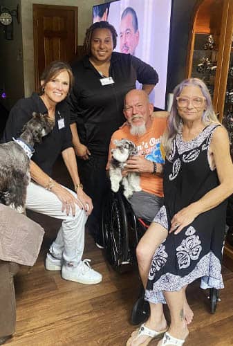 Female Caregiver with Senior Veteran Client and Family Holding Gift Muffins