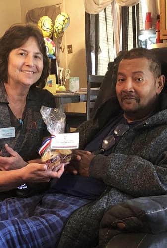 Female Caregiver Posing with African American Veteran Holding Gift Muffins