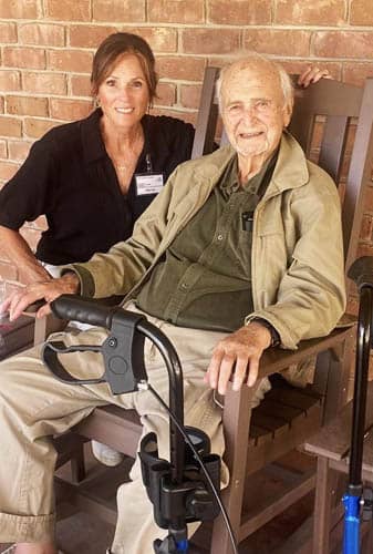 Senior Male Seated Posing with Caregiver and Gift Muffins