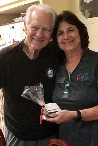 Senior Male Veteran and Female Caregiver Posing with Gift Muffin Package