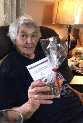 Seated Senior Woman Veteran Holding Up A Gift Package of Muffins