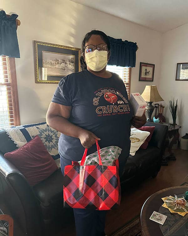 masked female caregiver holding gift bag