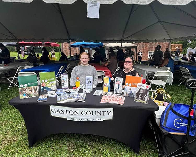 Two individuals sitting behind the Gaston County Veterans Services table.