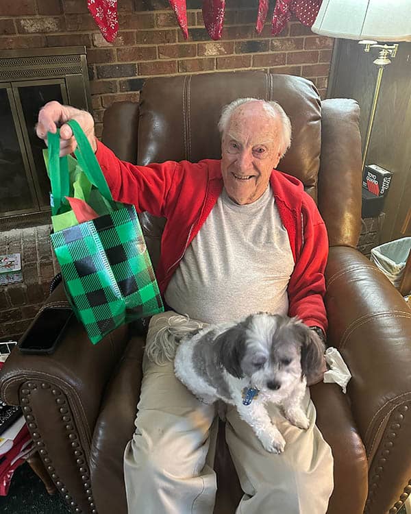 male client sitting with dog, holding gift bag