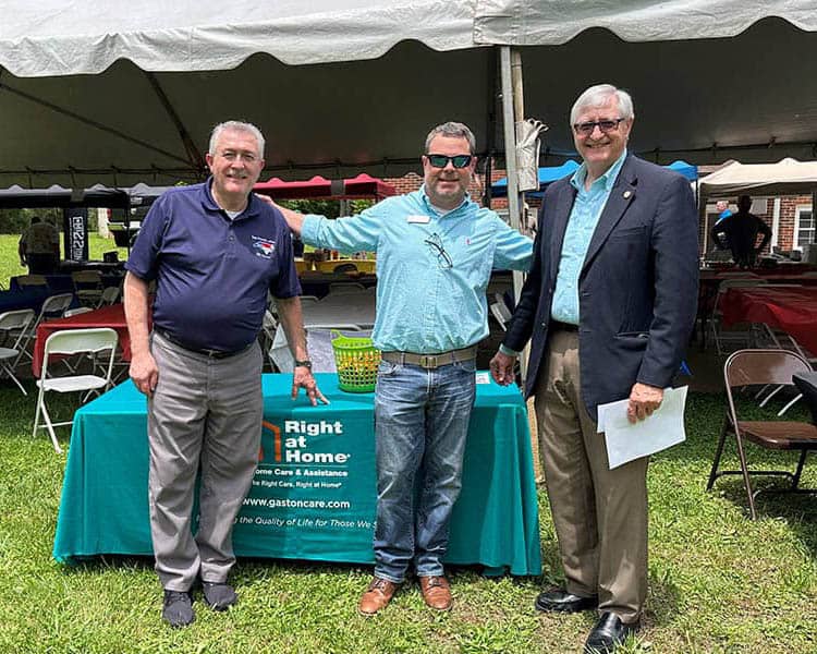 Owner Bill Osborne standing with two other men in front of a Right at Home table.