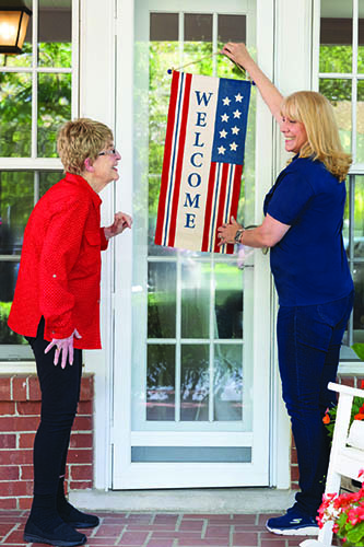 Female Caregiver Hanging Patriotic Flag With Female Client