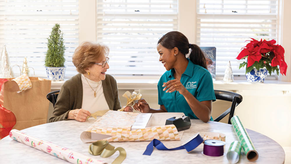 Right At Home Caregiver Helping A Senior Woman With Holiday Wrapping