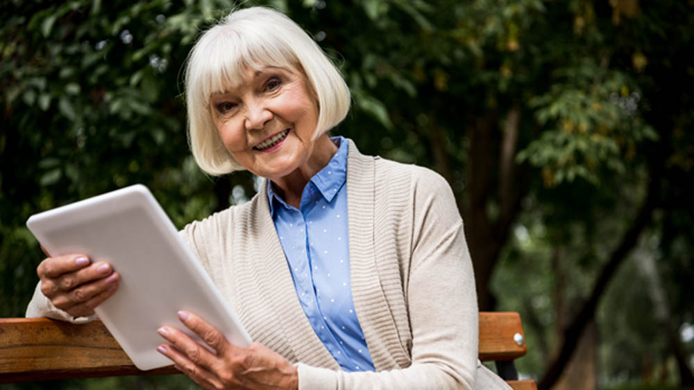 Senior Woman Viewing a Tablet Outdoors on a Bench