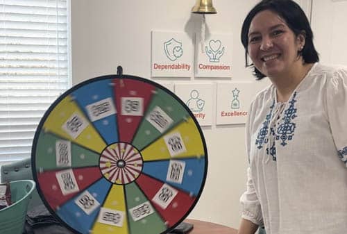 Female Caregiver Pose with the Prize Wheel at Right at Home Rockwall's Caregivers Week Festivities