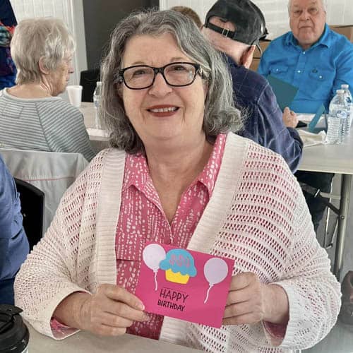 Senior Woman Sitting and Showing the Camera a Greeting Card She Wrote