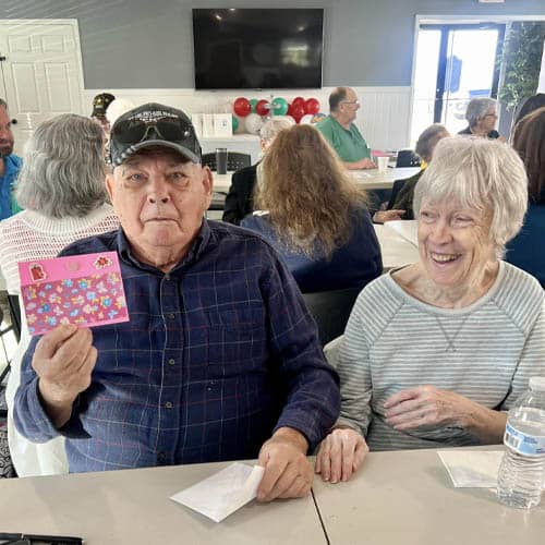 Senior Man and Woman Sitting and Showing the Camera a Greeting Card They Wrote