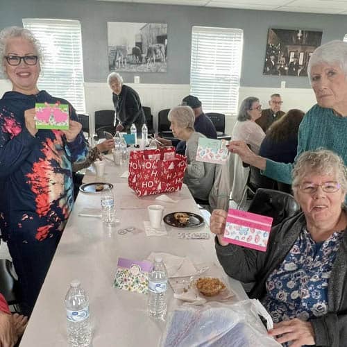 Group of Seniors at a Long Table Showing the Handwritten Cards They Made