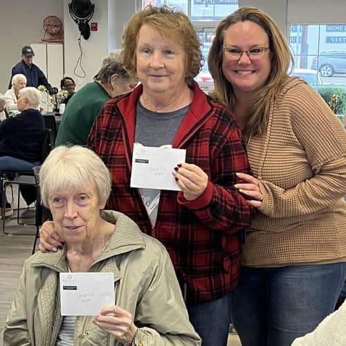One Senior Woman Sitting and Two Women Standing Posing Holding Up Cards 