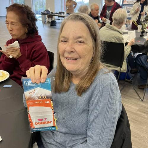 Senior Woman Holding Up a Winning Card at the Trinity Hospice Luncheon