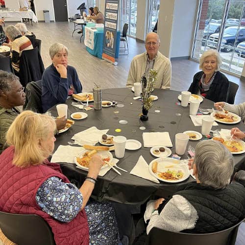 Table of Seniors Shown From a Height Enjoying a Luncheon Meal During the Trinity Hospice Luncheon