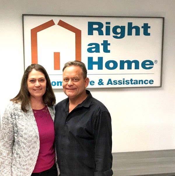 photo of Lynette and Chris Slagle in front of Right at Home sign in their office