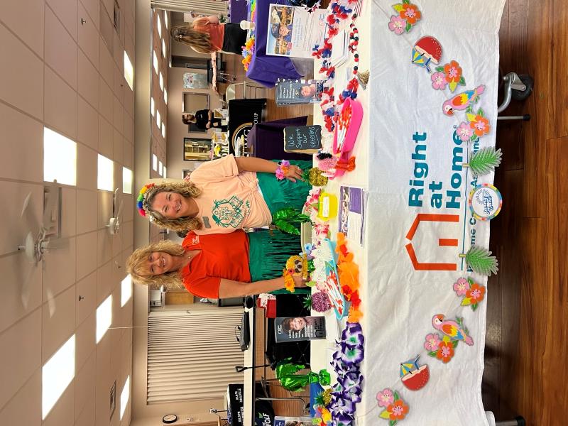 Holly and Wendi standing behind a table with a Right at Home tablecloth on it