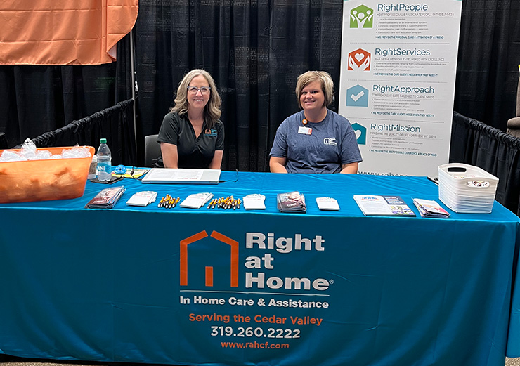 Stephanie Humphries and a staff member sit smiling at a health fair booth