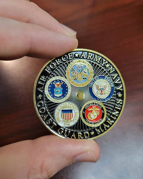 One side of a veterans coin showing the five military branches.