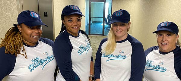Four female members of the Right at Home of Virginia Beach, VA office staff wearing Right at Home branded baseball attire. 