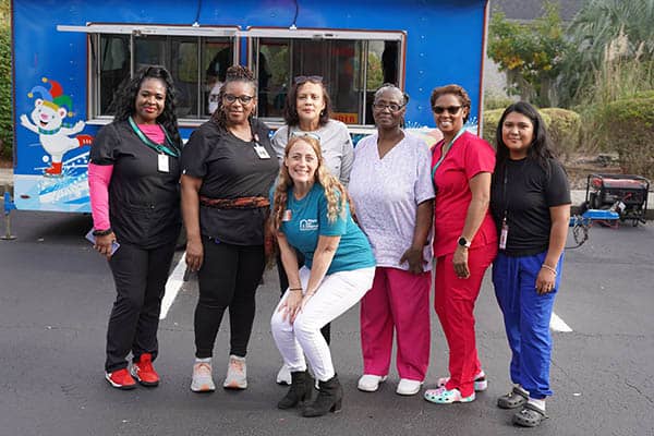 A group of Right at Home of Hilton Head, SC Caregivers and staff standing together in front of a kona ice truck