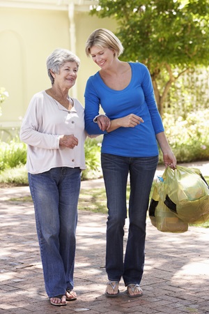 Woman helping senior walk.