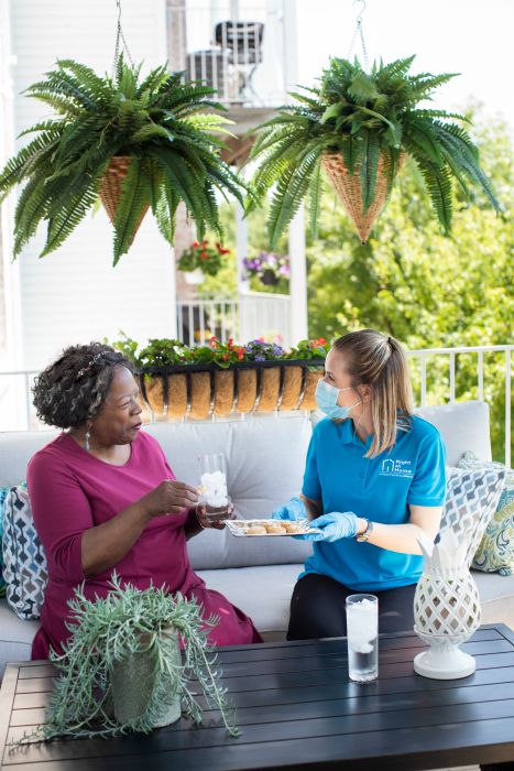 senior female and female caregiver enjoying refreshments 