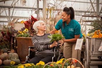 Senior female in wheelchair with female caregiver shopping for flowers