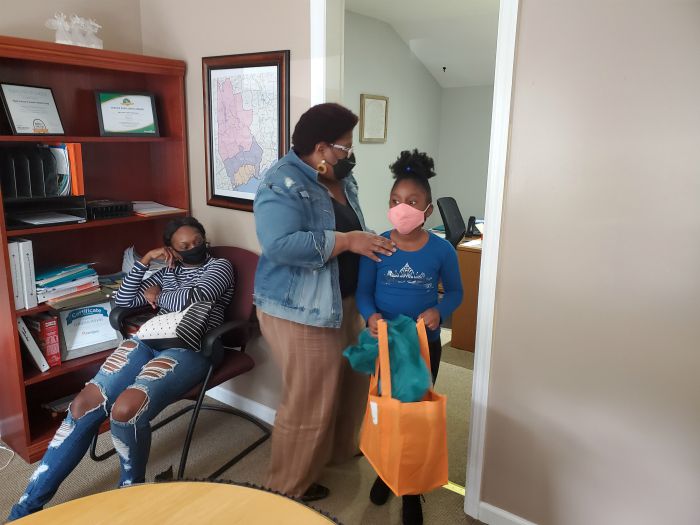 caregivers daughter holding a back to school bag from right at home in an office with two adult females