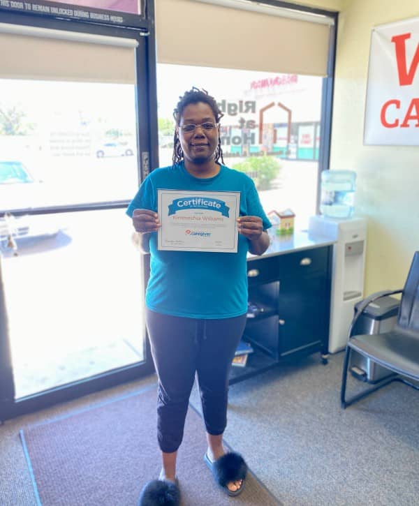 Kimmeshia standing holding employee of the month certificate