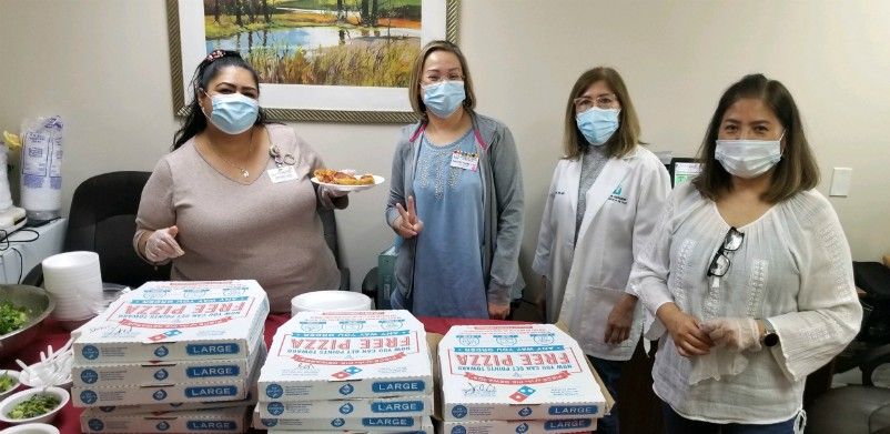 Caregivers with masks on in front of pizza boxes