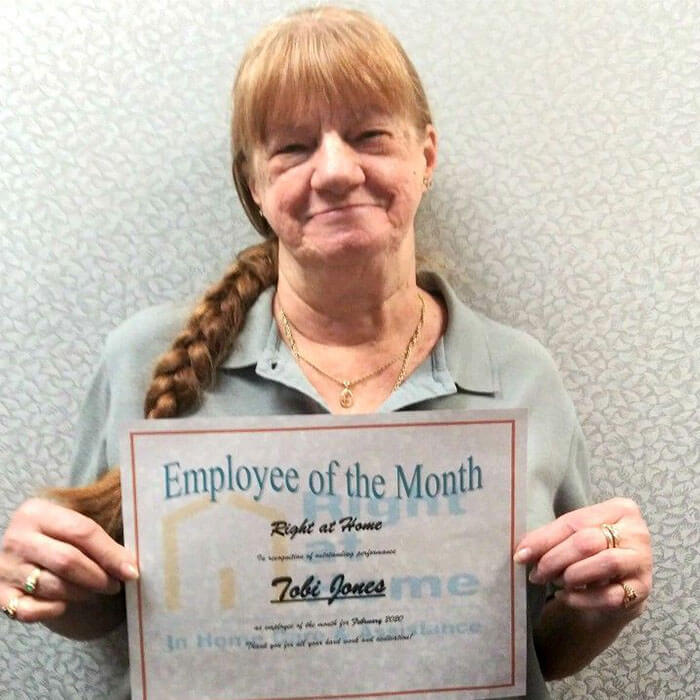 photo of caregiver holding employee of the month certificate