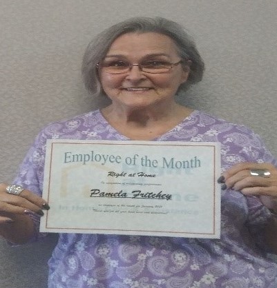 photo of caregiver in scrubs holding employee of the month certificate