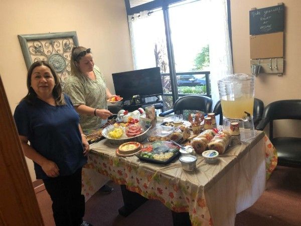 Couple of caregivers next to table of food 