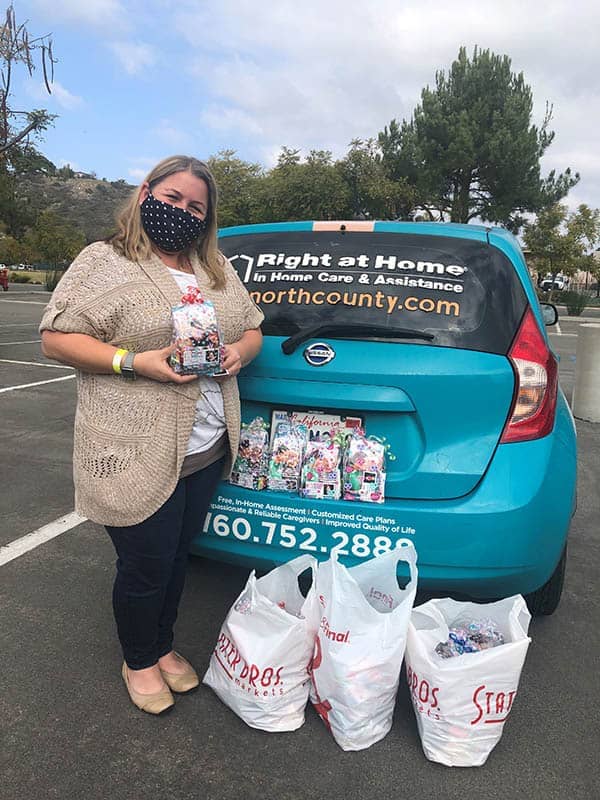 Carmen Sanchez with treat bags at the back of wrapped Right at Home vehicle