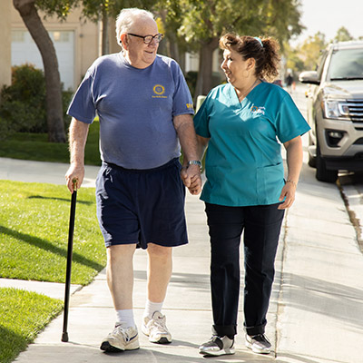 Female Caregiver Walking Outdoors With A Male Client