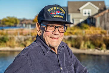 Senior Veteran Man by a Lake with a Military Patch on His Baseball Cap