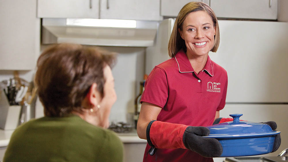 Female caregiver baking for female senior client
