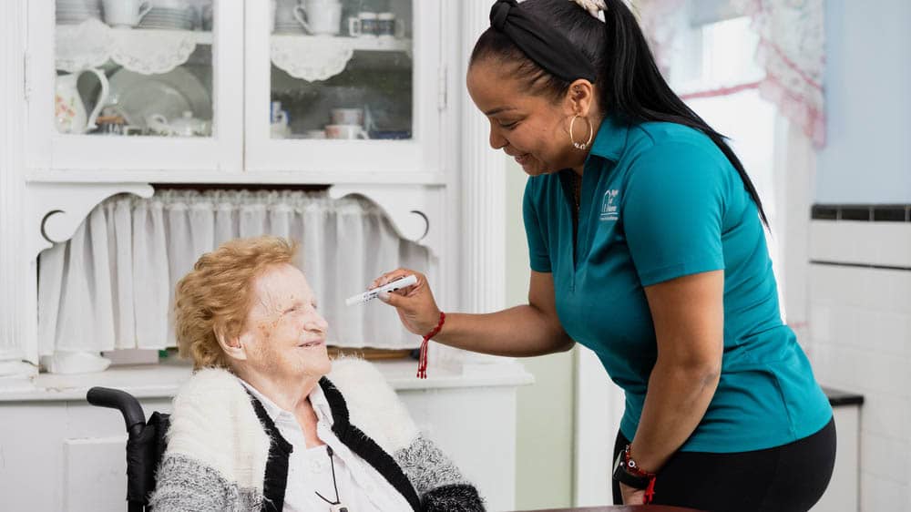 A female caregiver is checking a female senior's eyes
