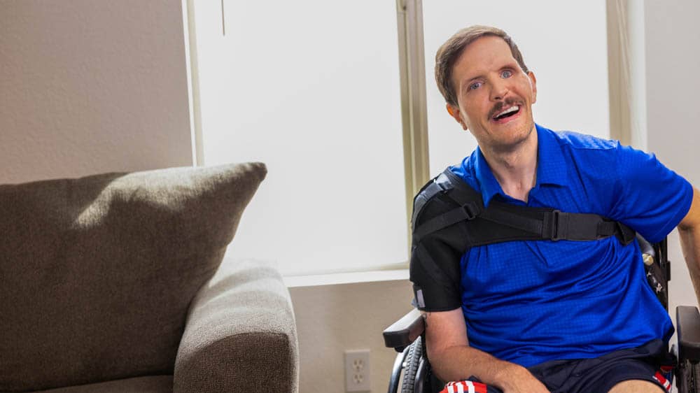 Disabled adult male sitting in a wheelchair in a living room.