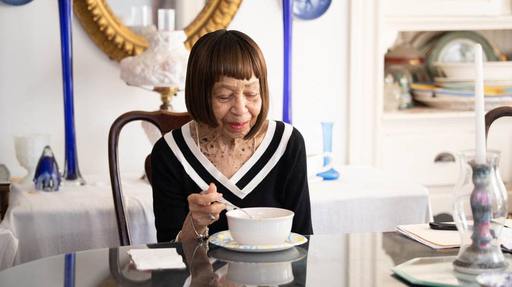 Senior female alone at a kitchen table enjoying a bowl of soup