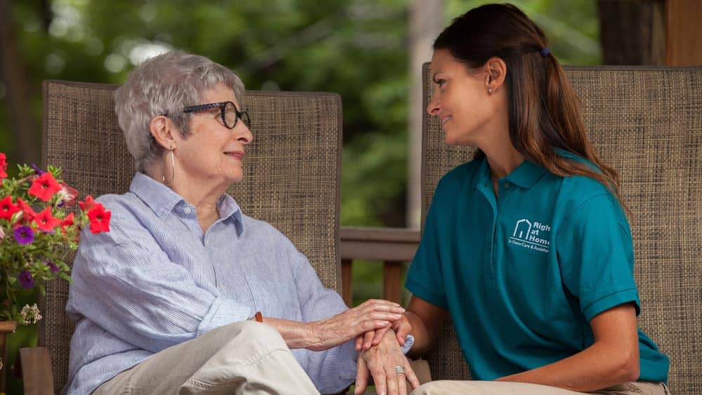female Right at Home caregiver sitting outside with a female senior client