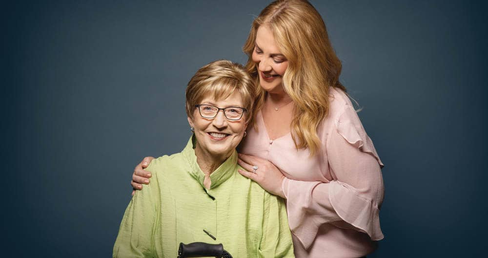 A senior mother and adult daughter posing together for a portrait