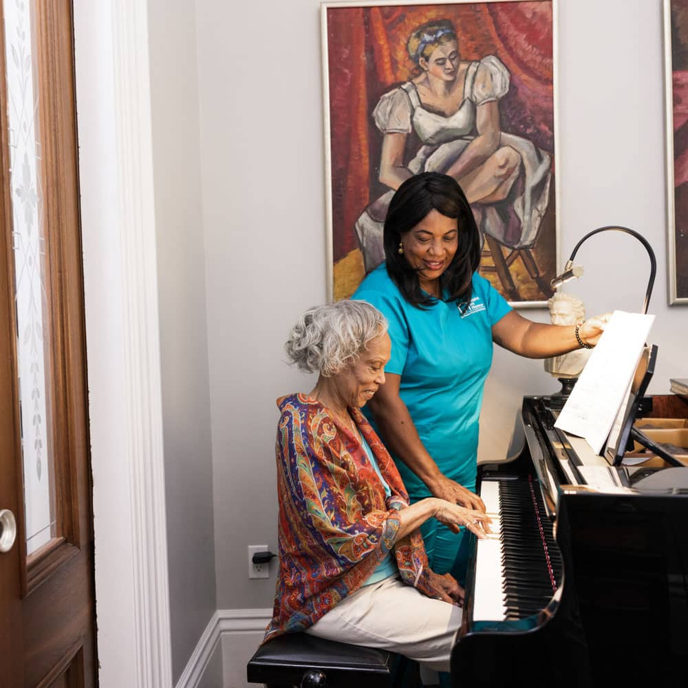 Caregiver watching a senior play the piano.