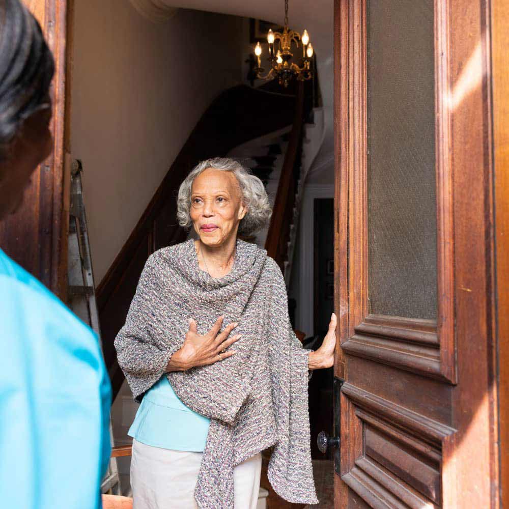 Female senior greeting the caregiver outside the door of her house.