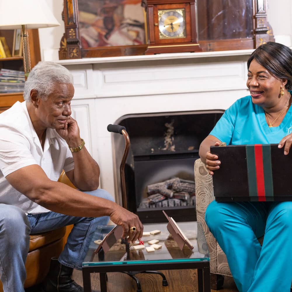 Caregiver and senior sitting in front of fire place playing games