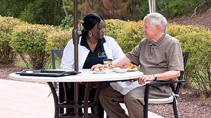 caregiver with senior outside under umbrella